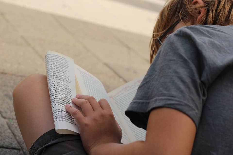 Young boy reading a text book.